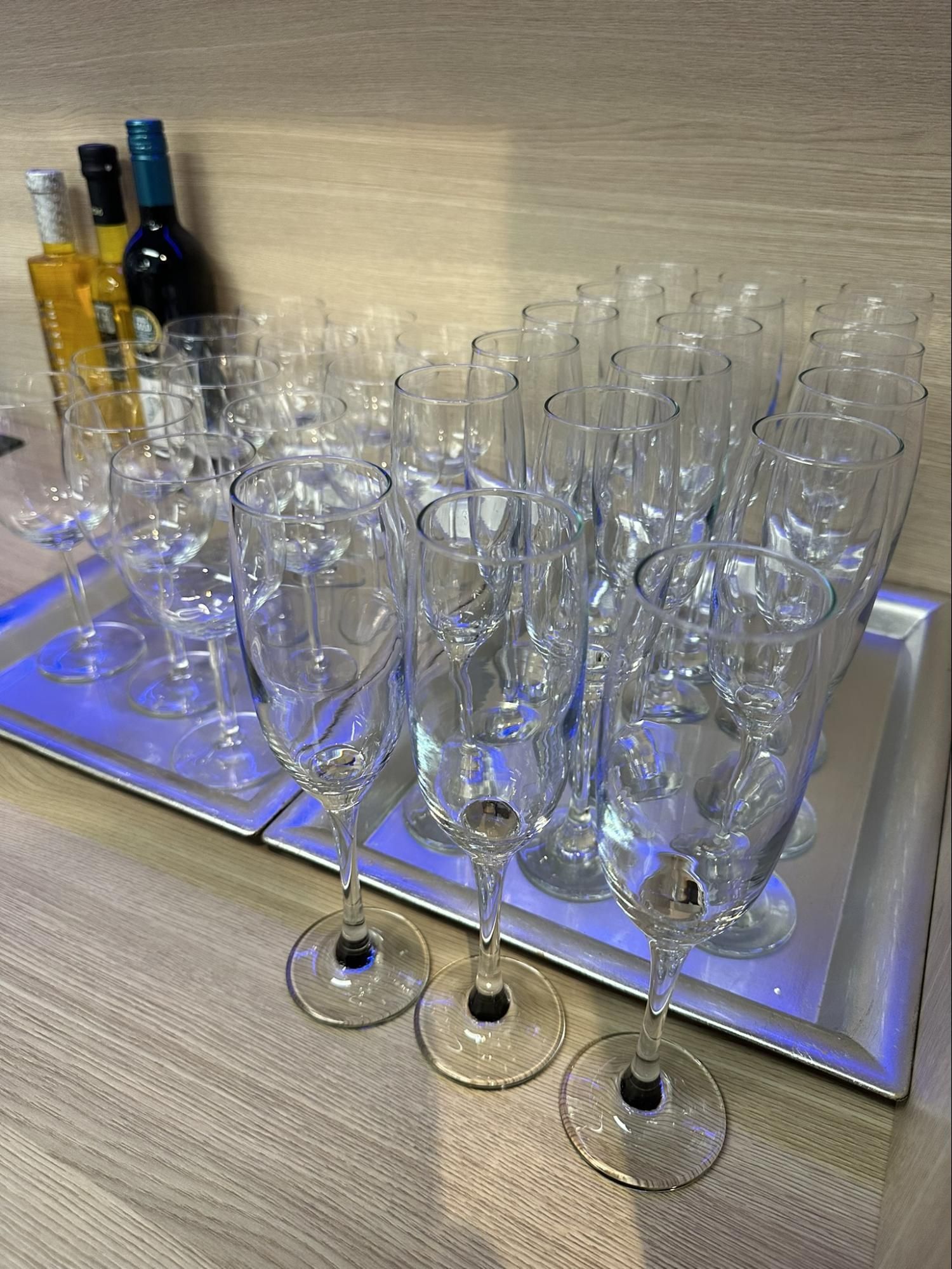 Champagne glasses arranged on a tray with bottles in the background.