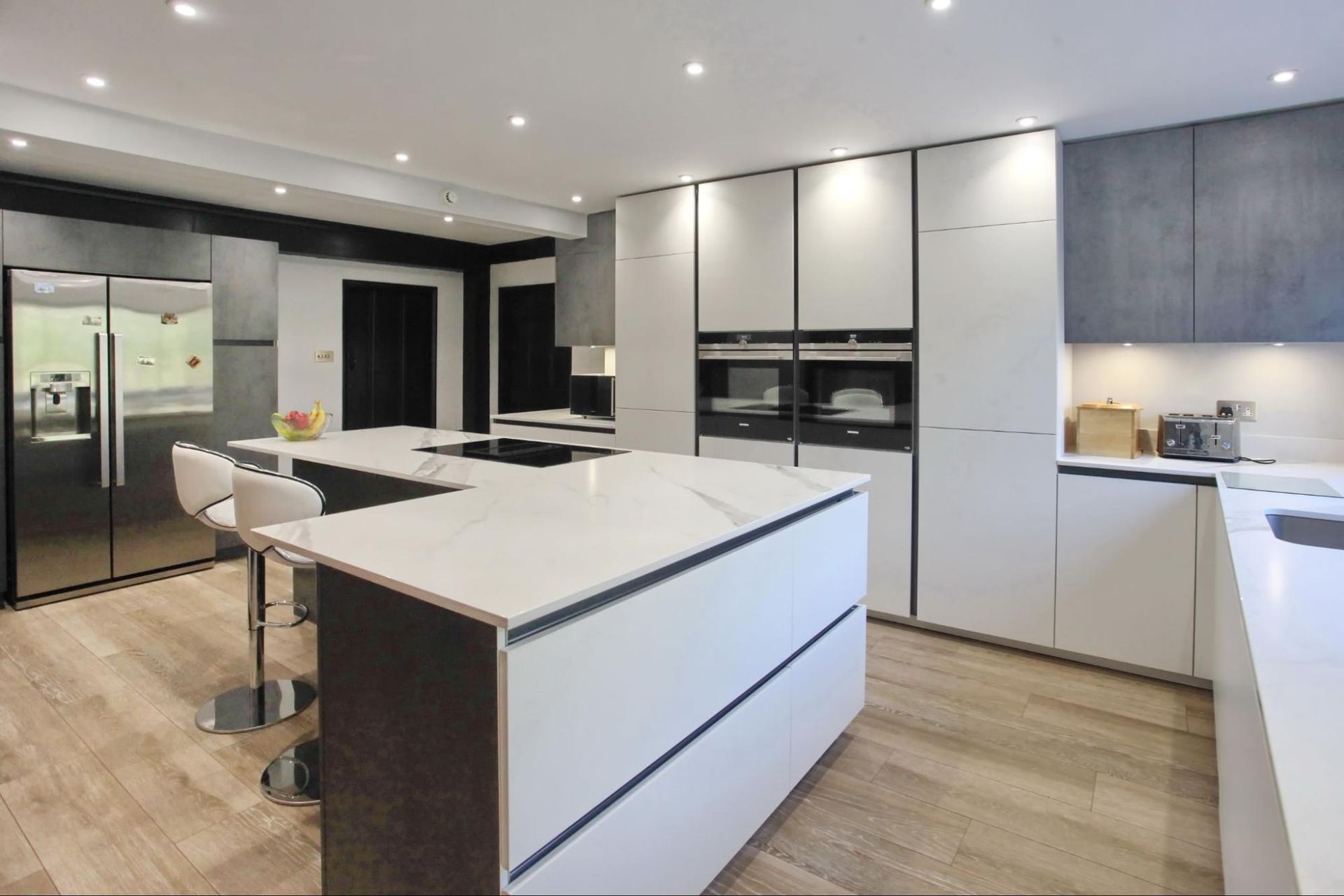 Modern kitchen with white countertops, dark cabinetry, and two islands.