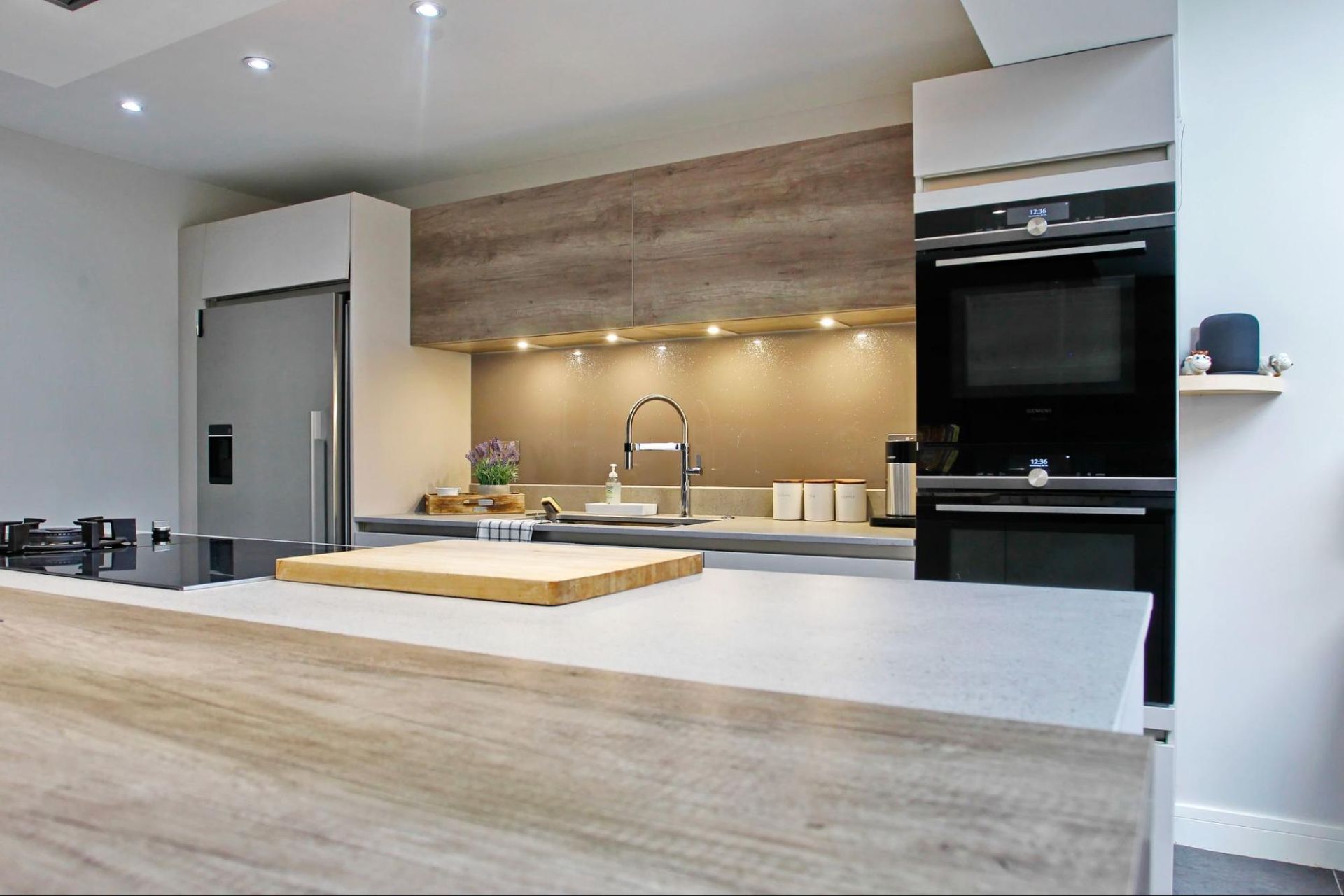 Modern kitchen with light wood accents, stainless steel appliances, and a gray countertop island.
