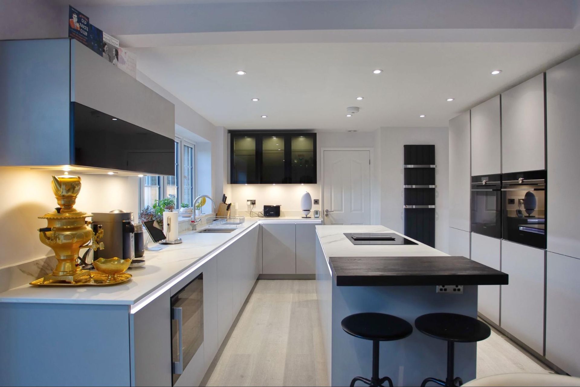 Modern kitchen with gray cabinets, island with black countertop, and recessed lighting.