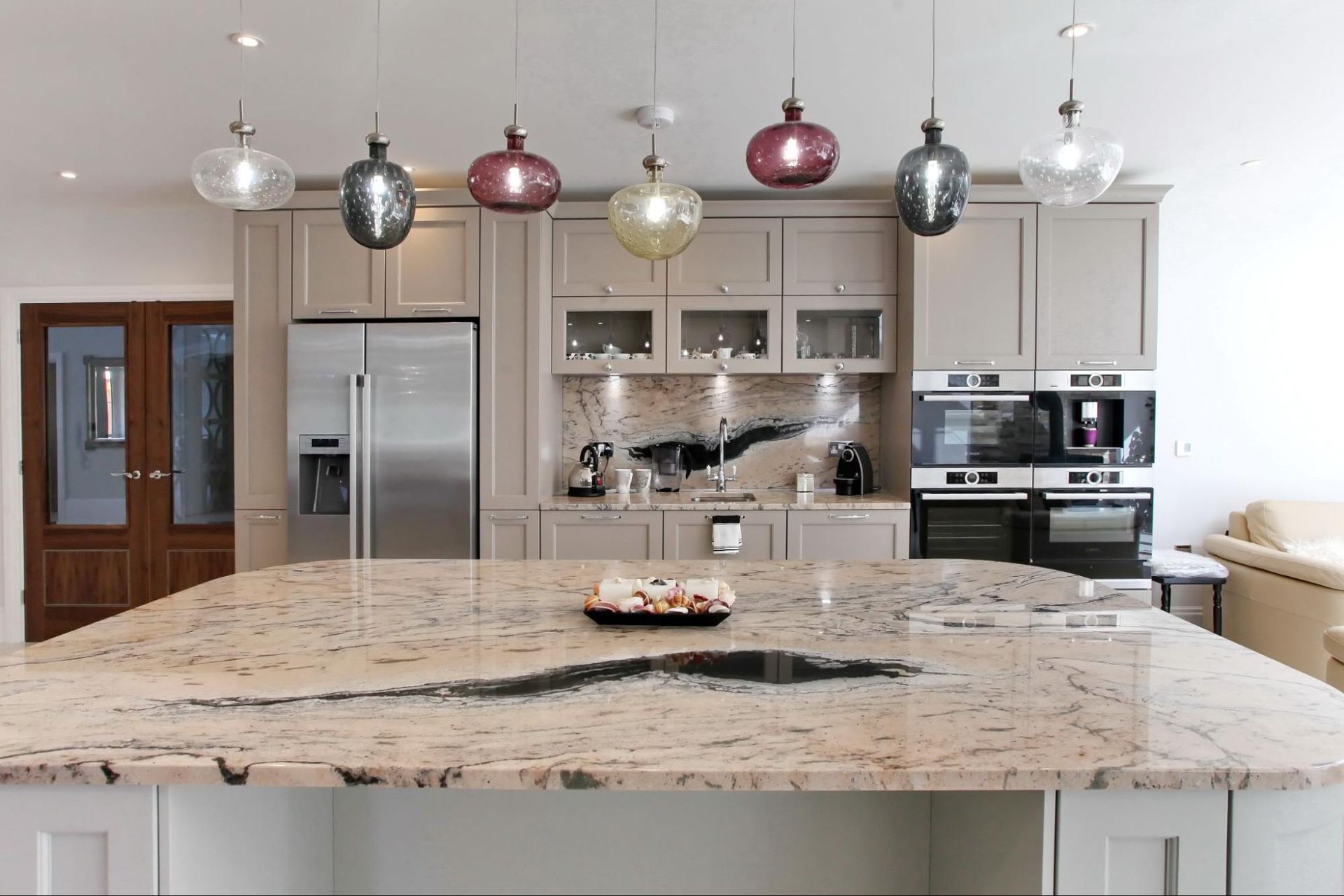 Modern kitchen with large island, granite countertop, stainless steel appliances, pendant lights.