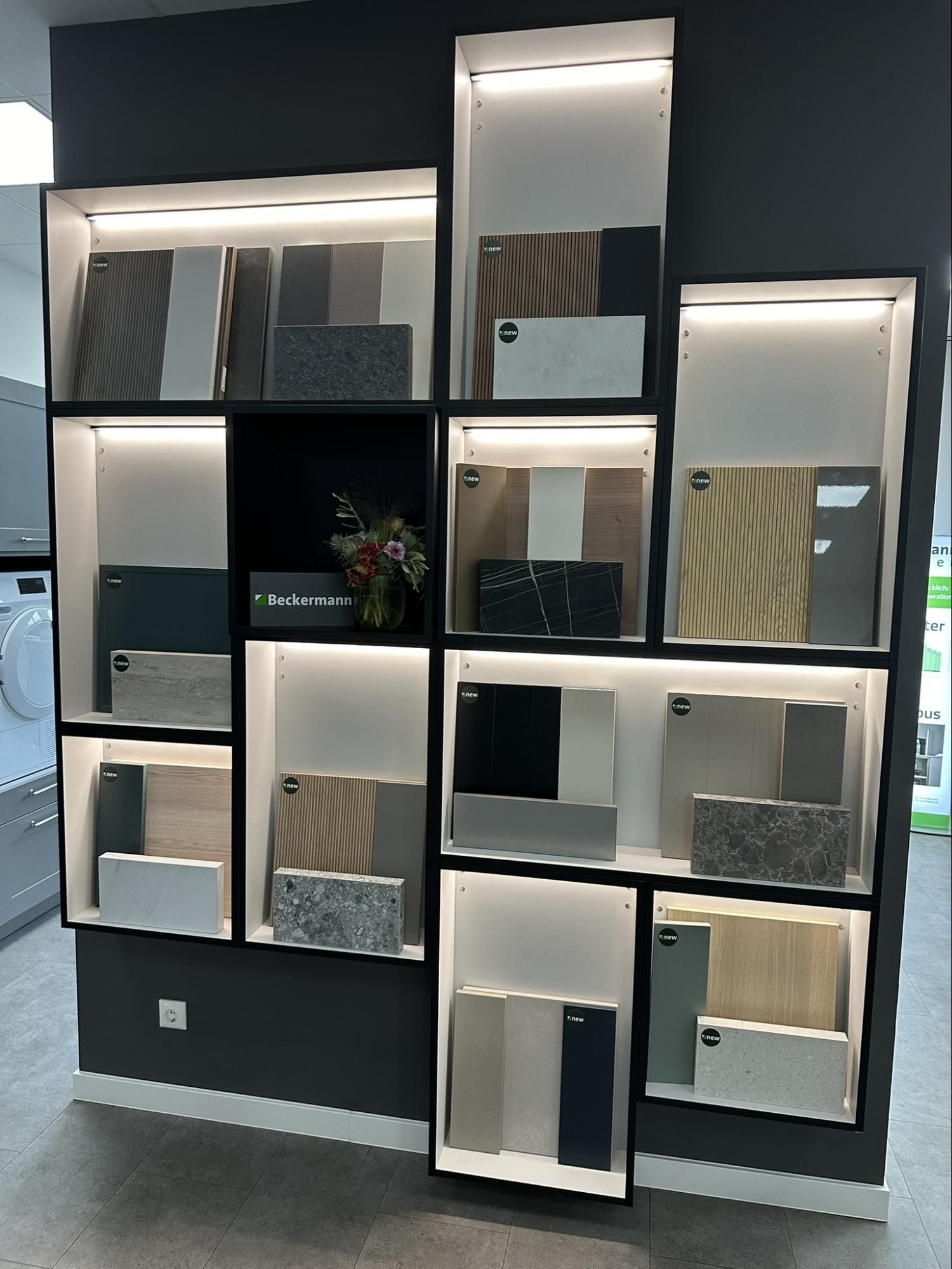 Display of tile samples in illuminated cubbyholes on a dark wall.