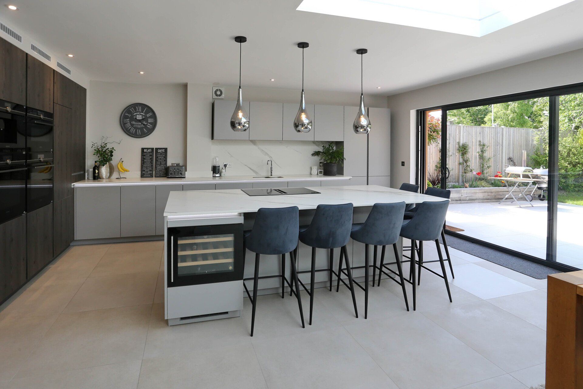 Modern kitchen with large island, pendant lights, and sliding glass doors to a patio.