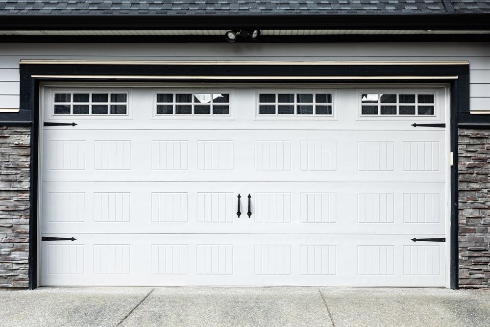 White two-car garage door with small windows on a modern house facade