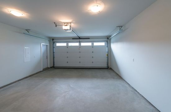 Empty residential garage with gray concrete floor and closed white sectional door