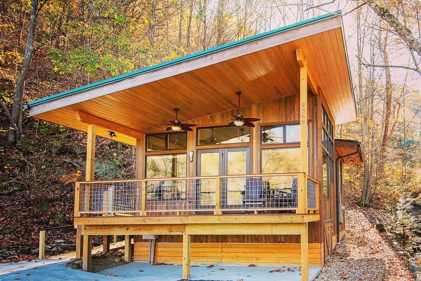 A small wooden house with a large deck in the woods.