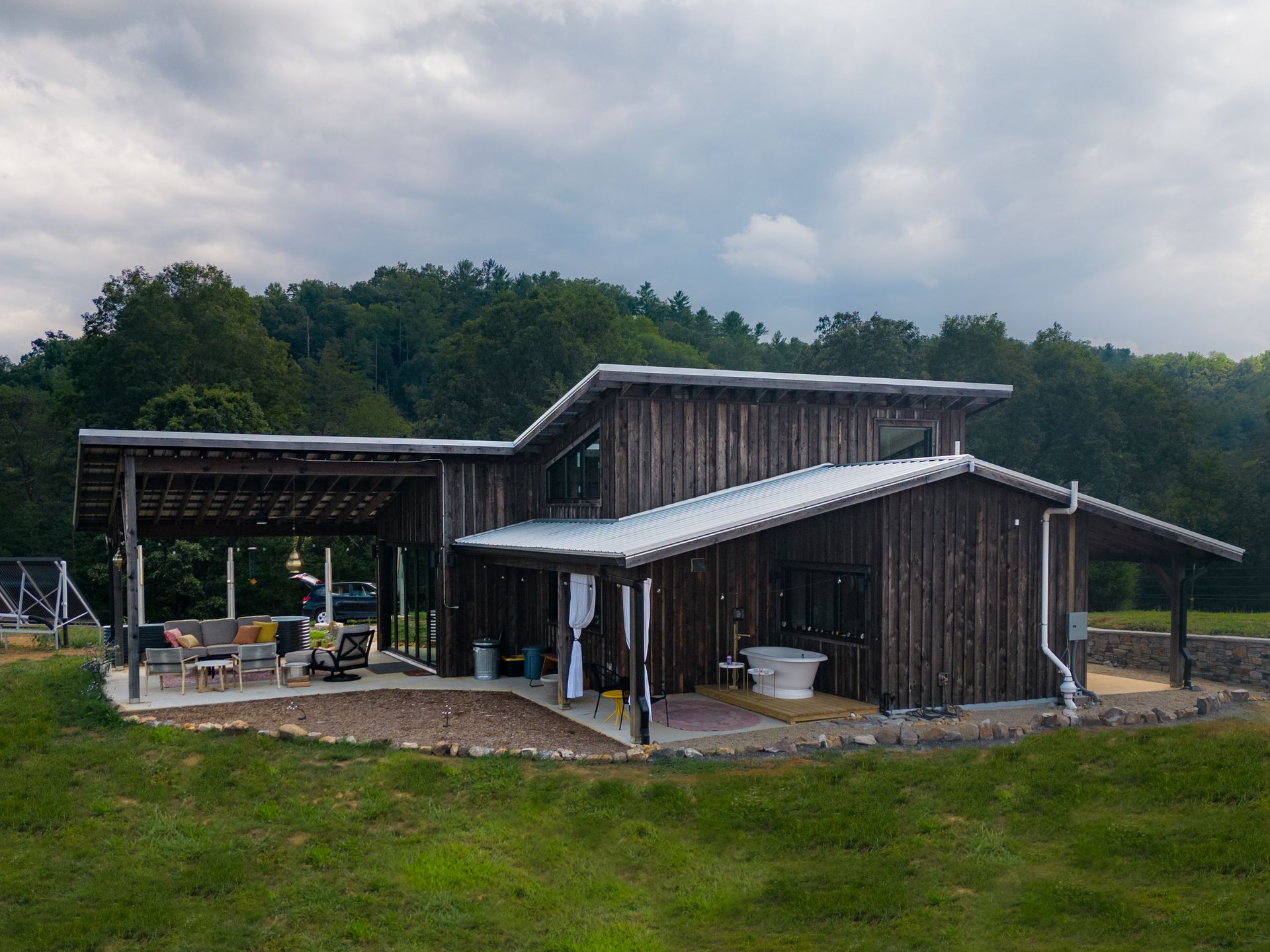 A large wooden house with a white roof is sitting in the middle of a grassy field.