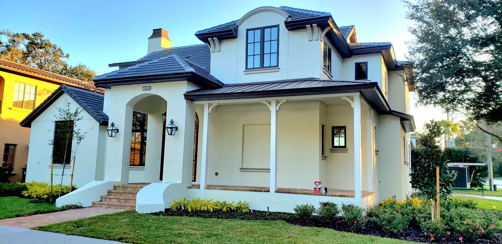 A white house with a porch is sitting on top of a lush green lawn.
