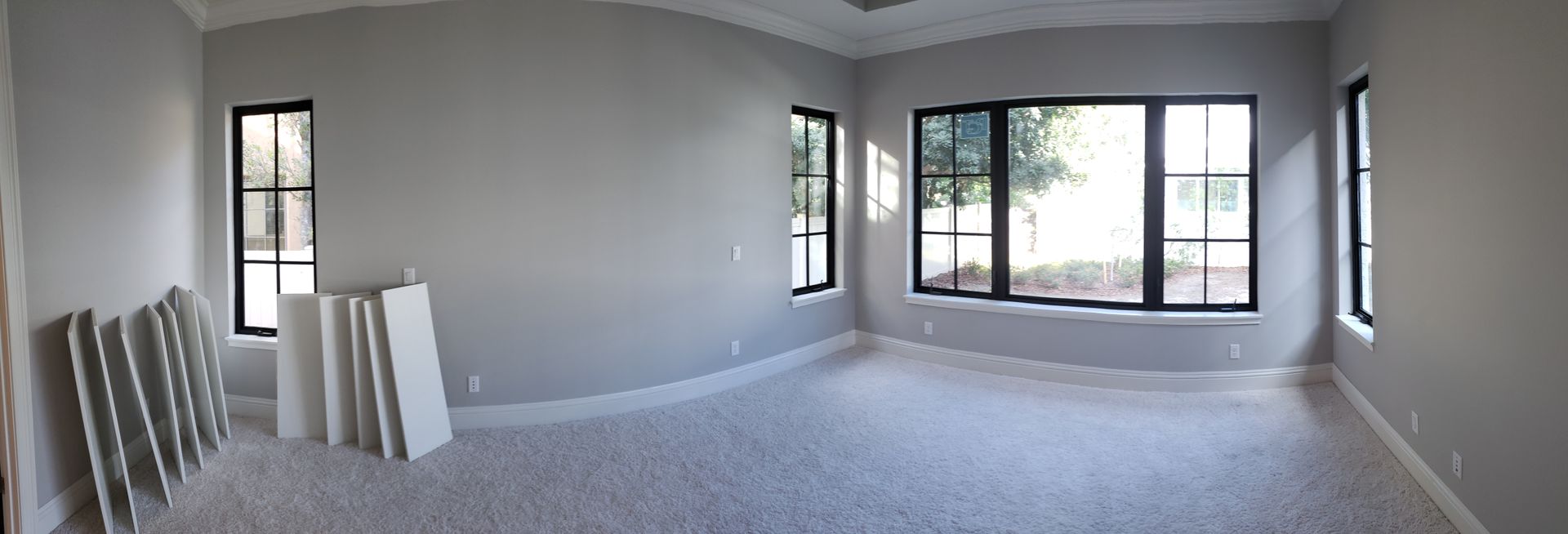 A large empty room with a lot of windows and a carpeted floor.