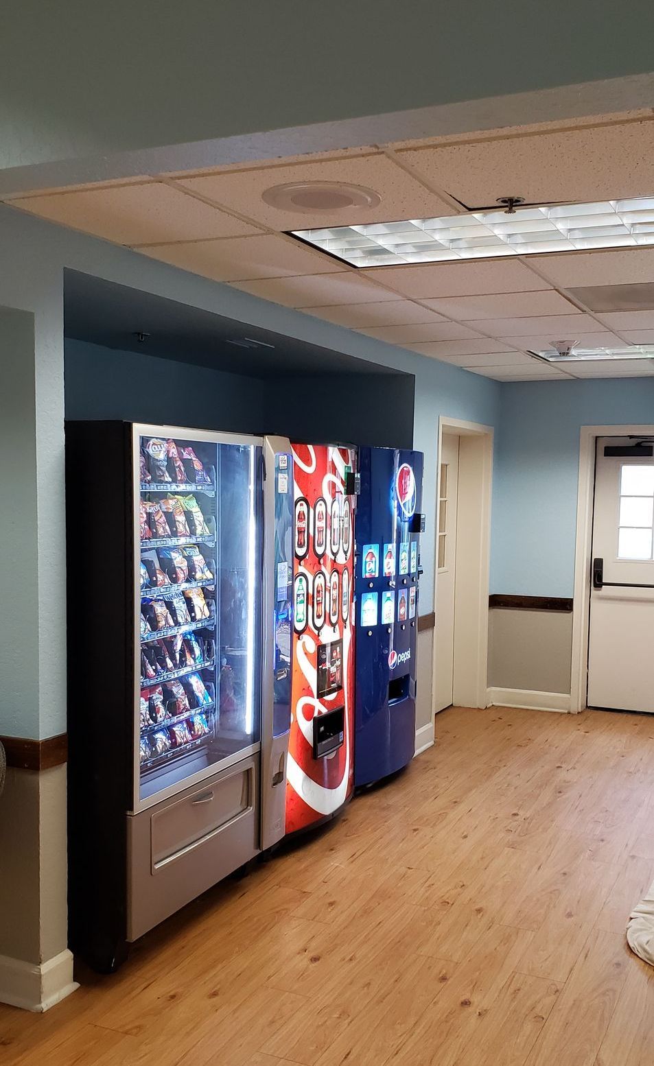 A hallway filled with vending machines and a door.