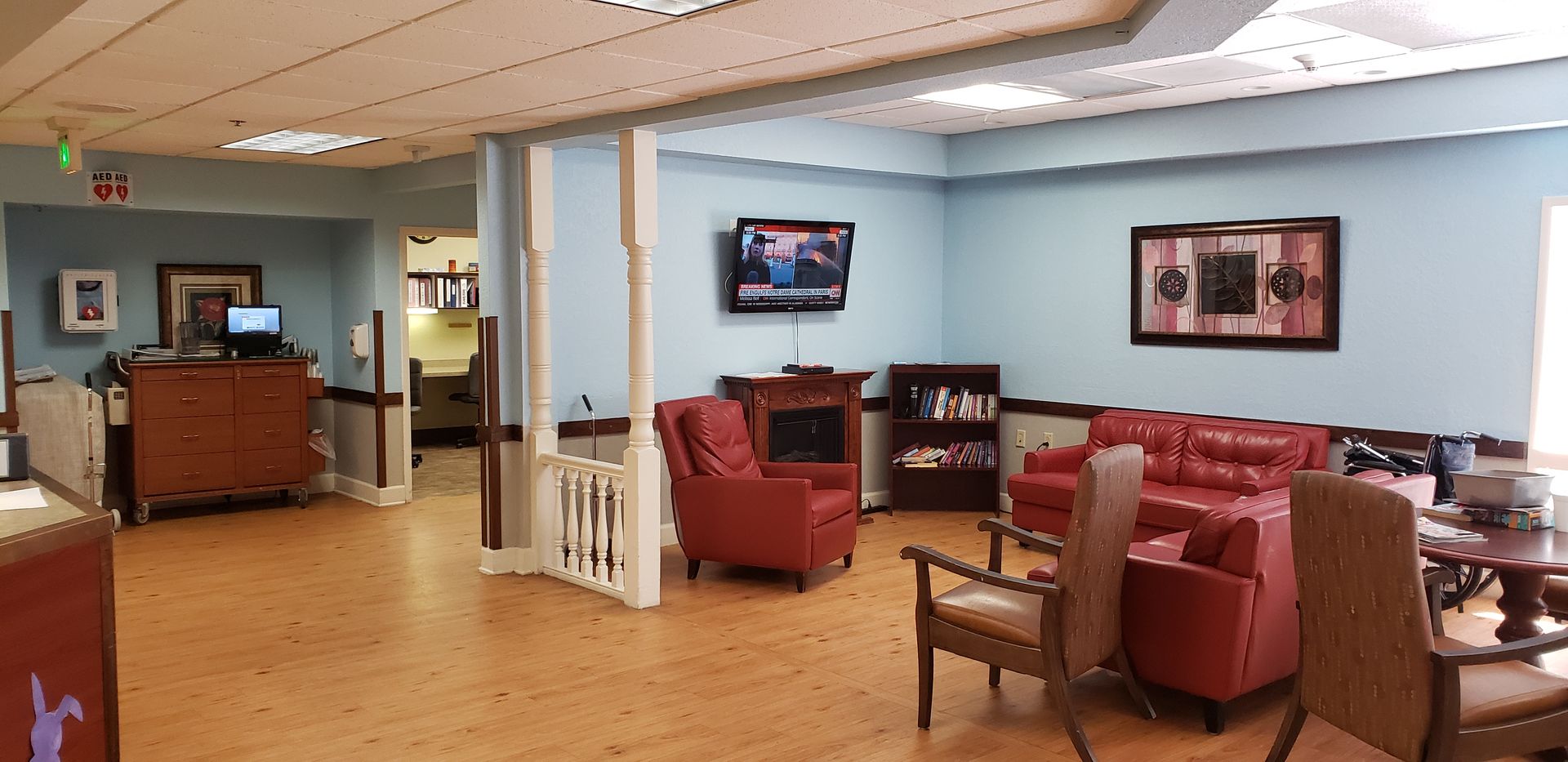 Interior shot of a waiting room with red furniture, a TV, and light blue walls.