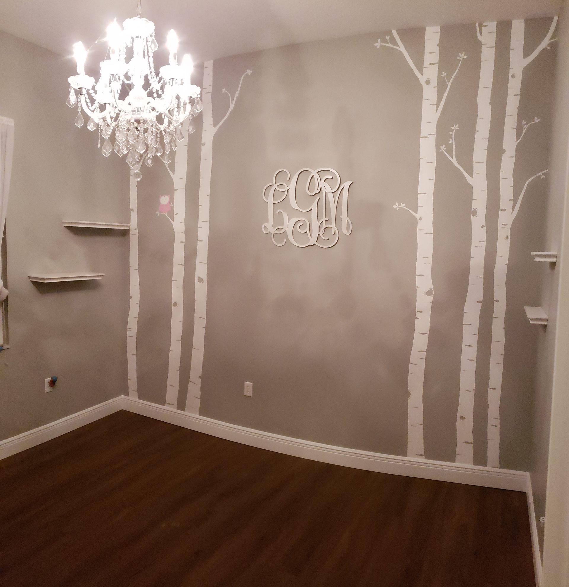 A room with a chandelier and a monogram on the wall