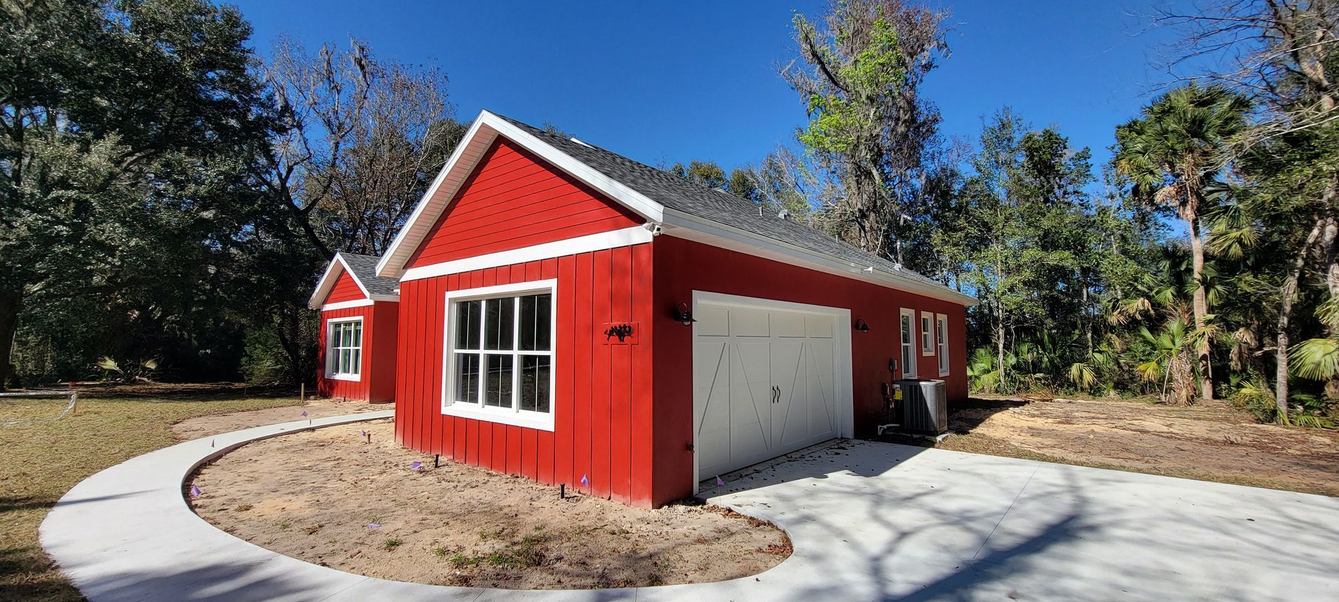 A red and white garage with a concrete driveway in front of it.