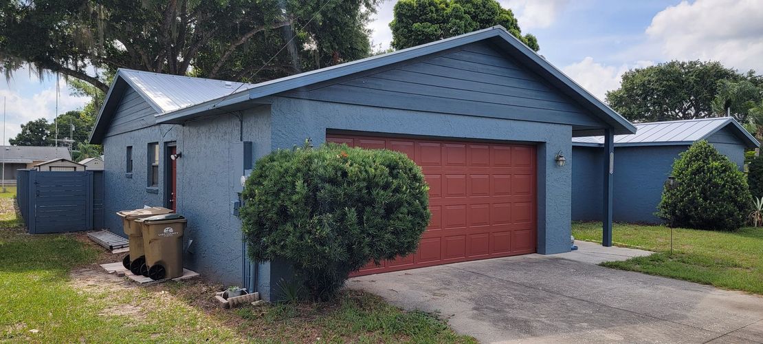A blue house with a red garage door is for sale.
