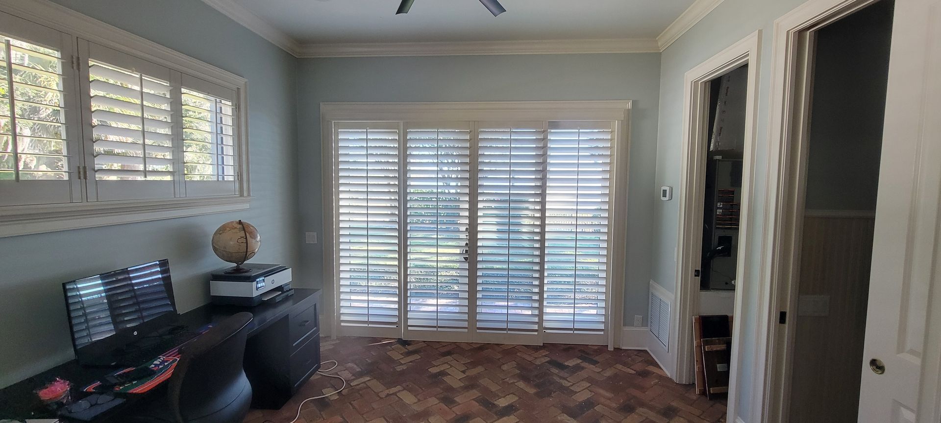 A living room with sliding glass doors and shutters on the windows.