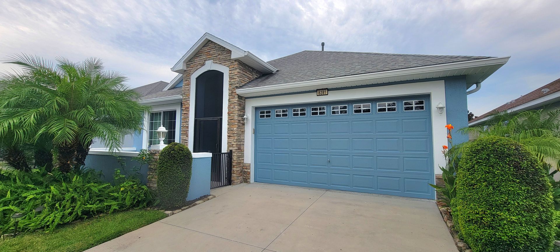 A blue house with a blue garage door and a screened in porch.