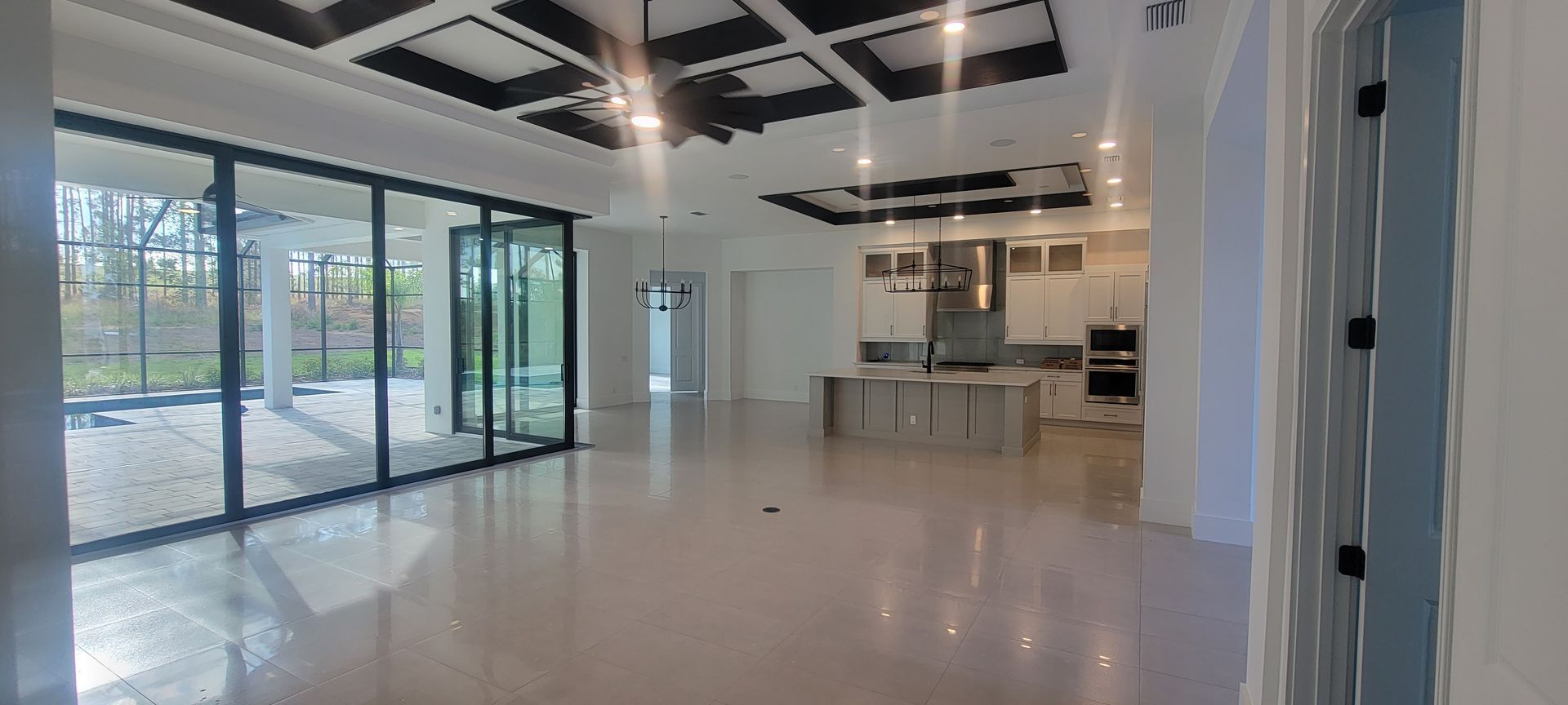Bright open modern kitchen and living space with large windows and glossy floors