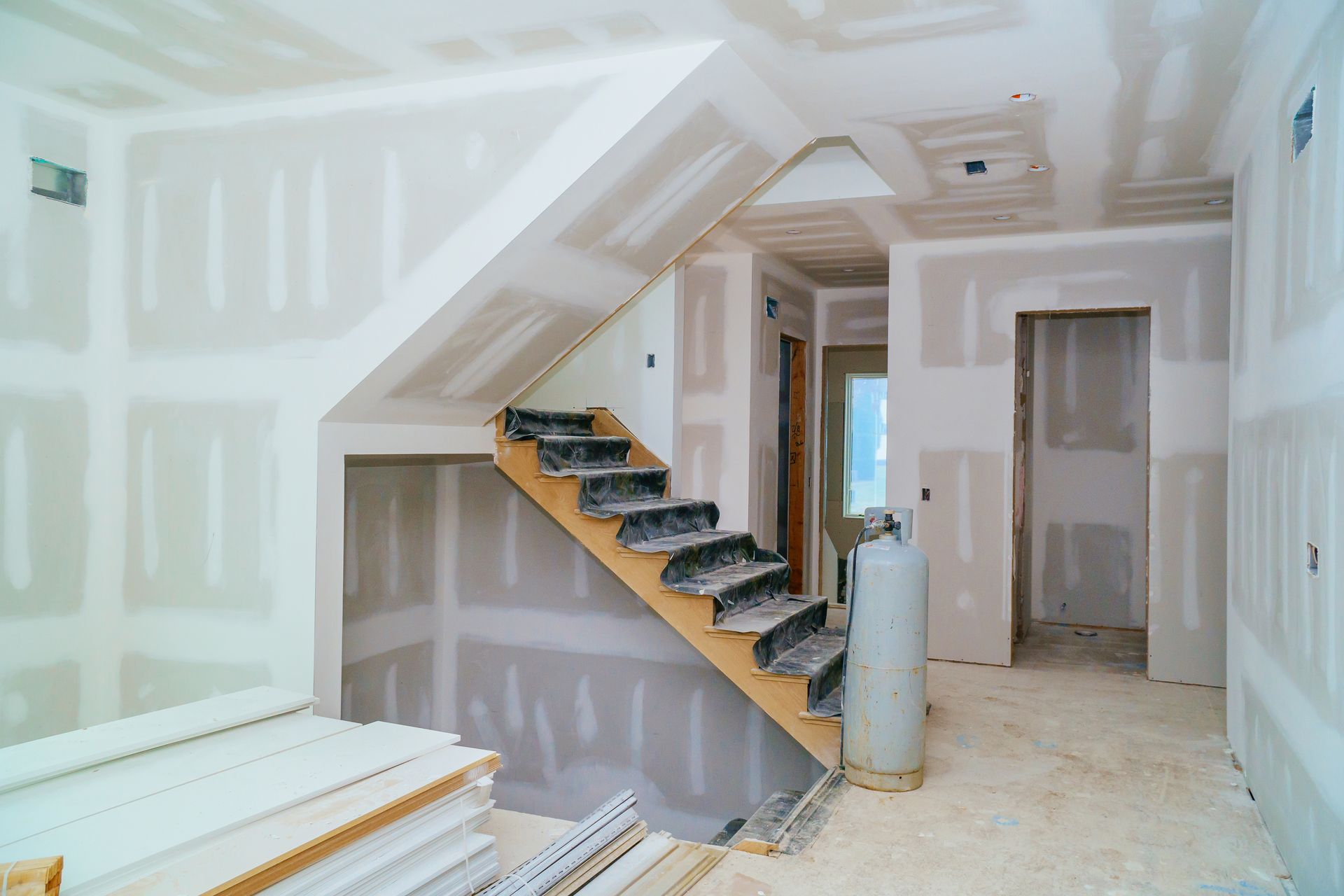 Unfinished room with drywall, staircase, and construction materials on the floor