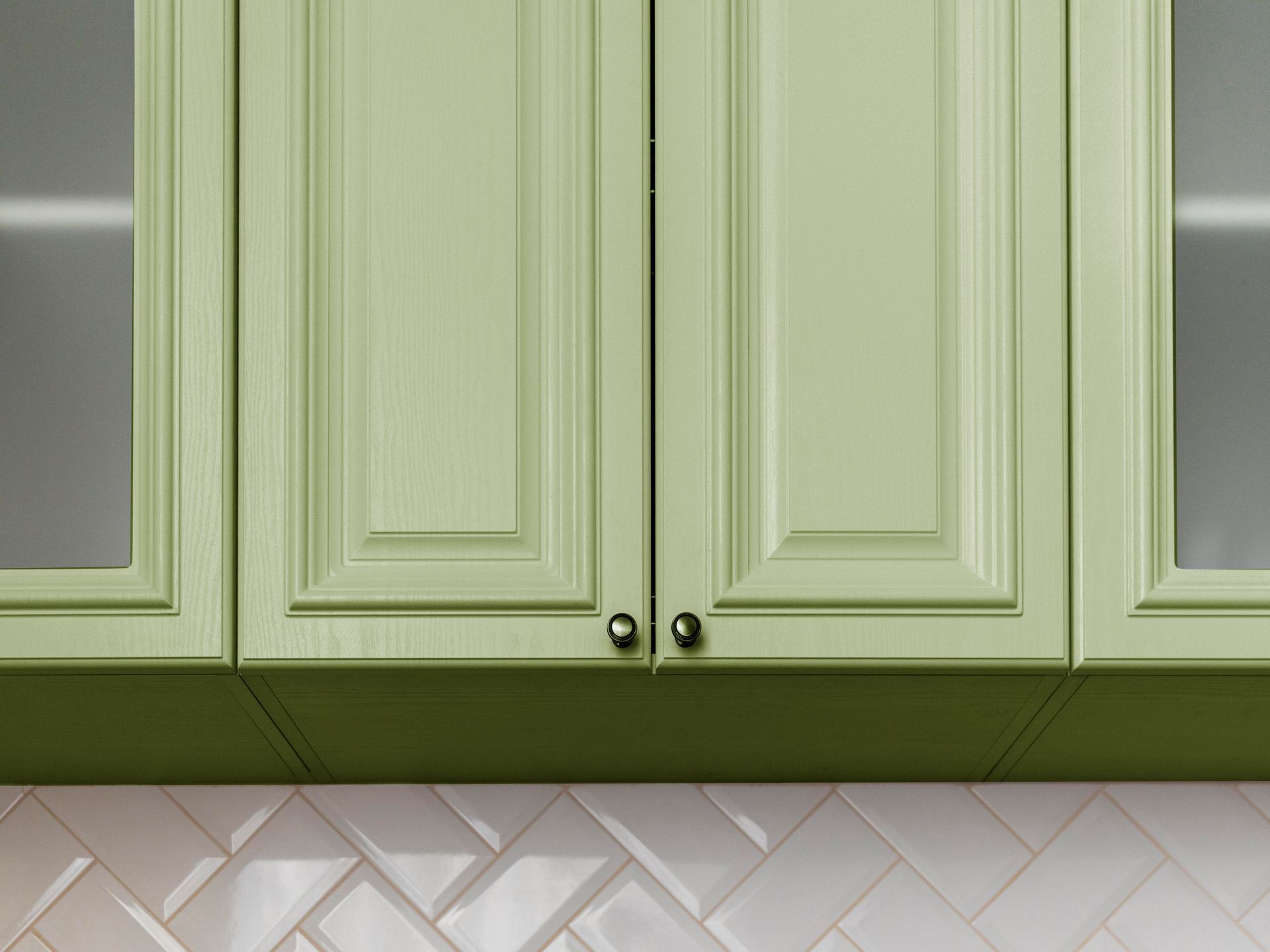 A kitchen with green cabinets and a black sink.