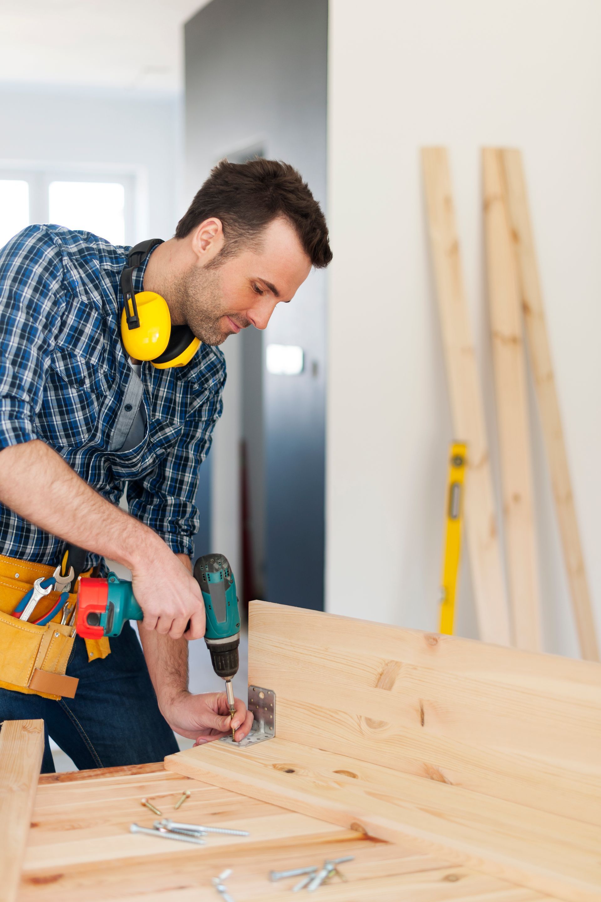 A man is using a drill to drill a hole in a piece of wood.