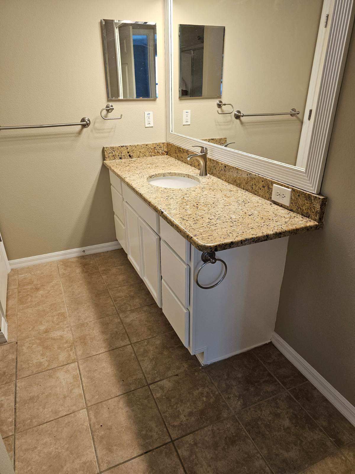 A bathroom with a sink , mirror and towel racks.