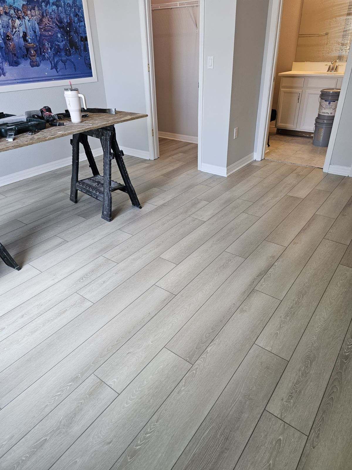 A room with a wooden floor , a table , and a picture on the wall.
