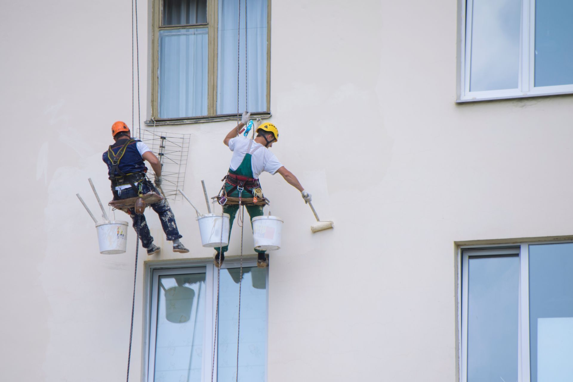 Two men are painting the side of a building.