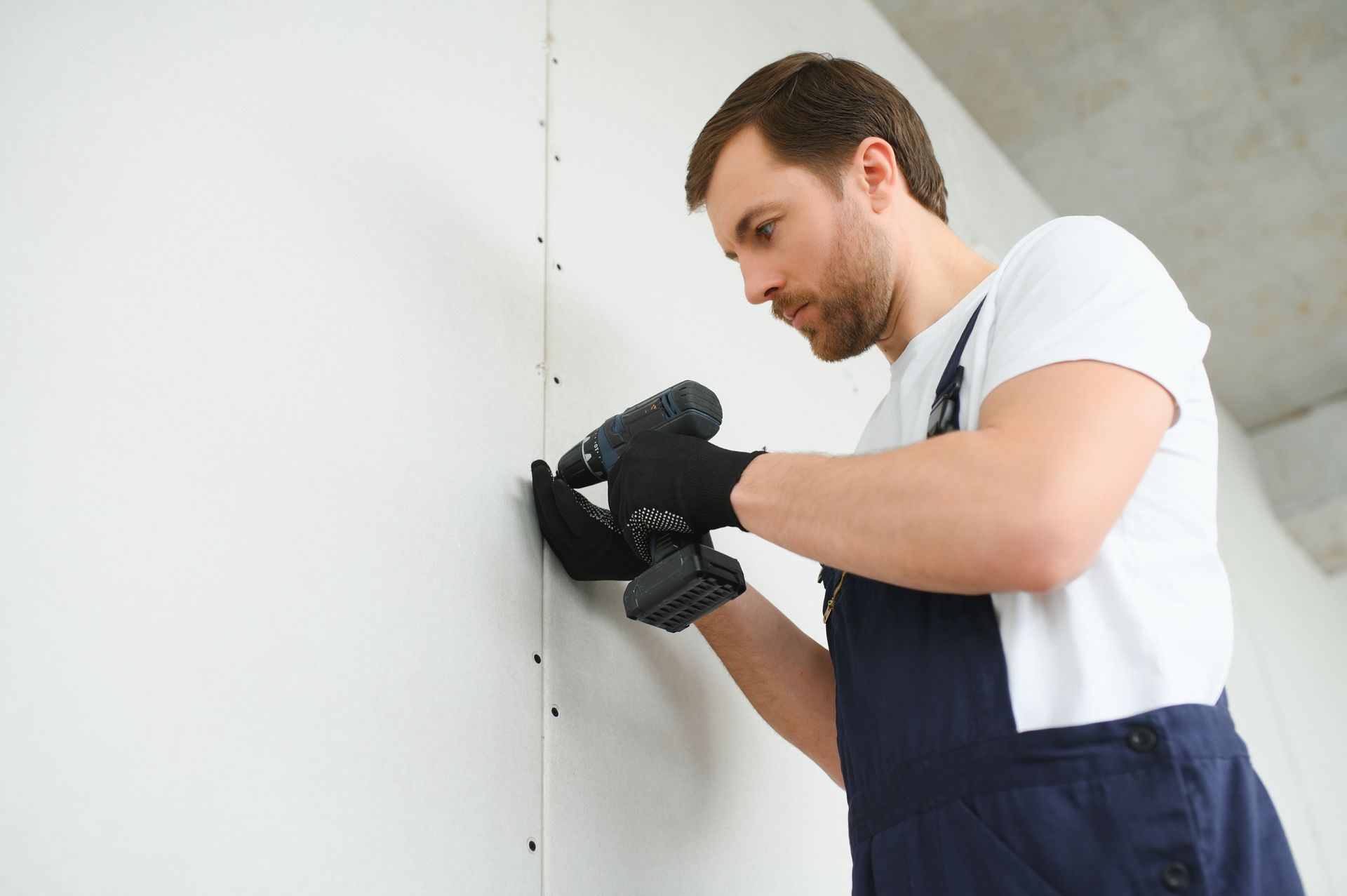 A man is using a drill on a wall.