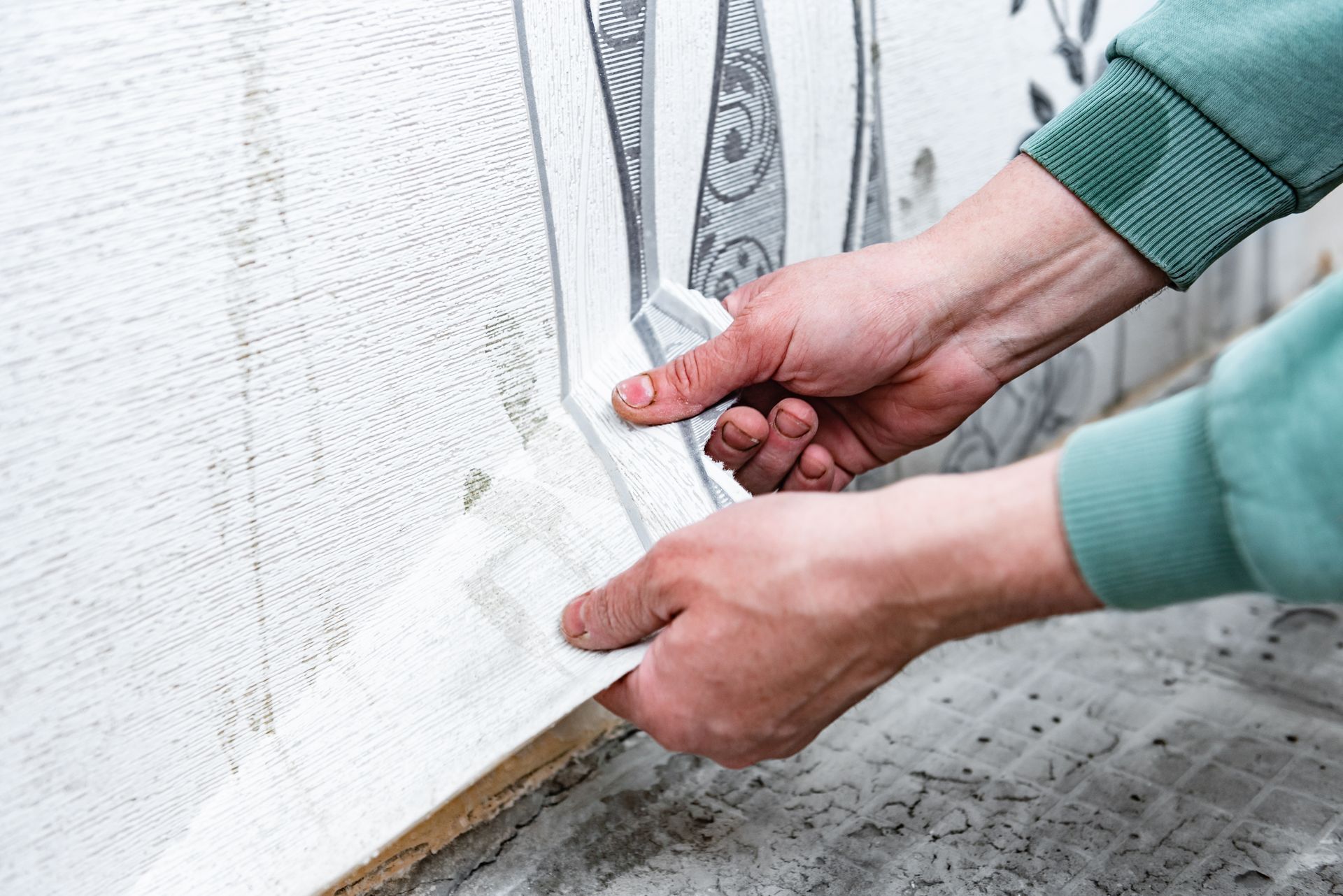 A person is peeling off a piece of wallpaper from a wall.