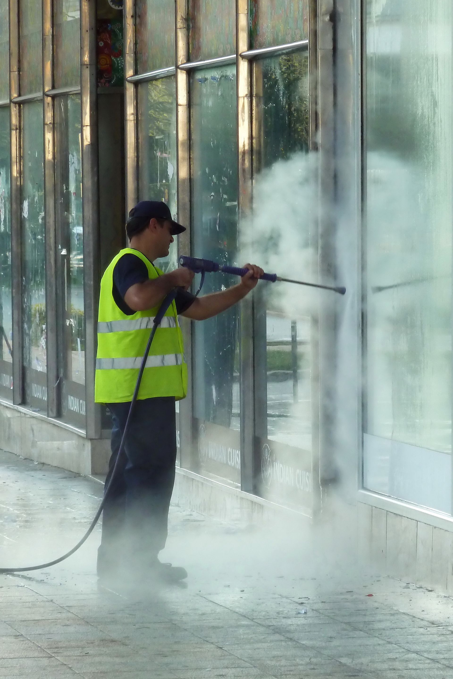 A man is cleaning a building with a high pressure washer.
