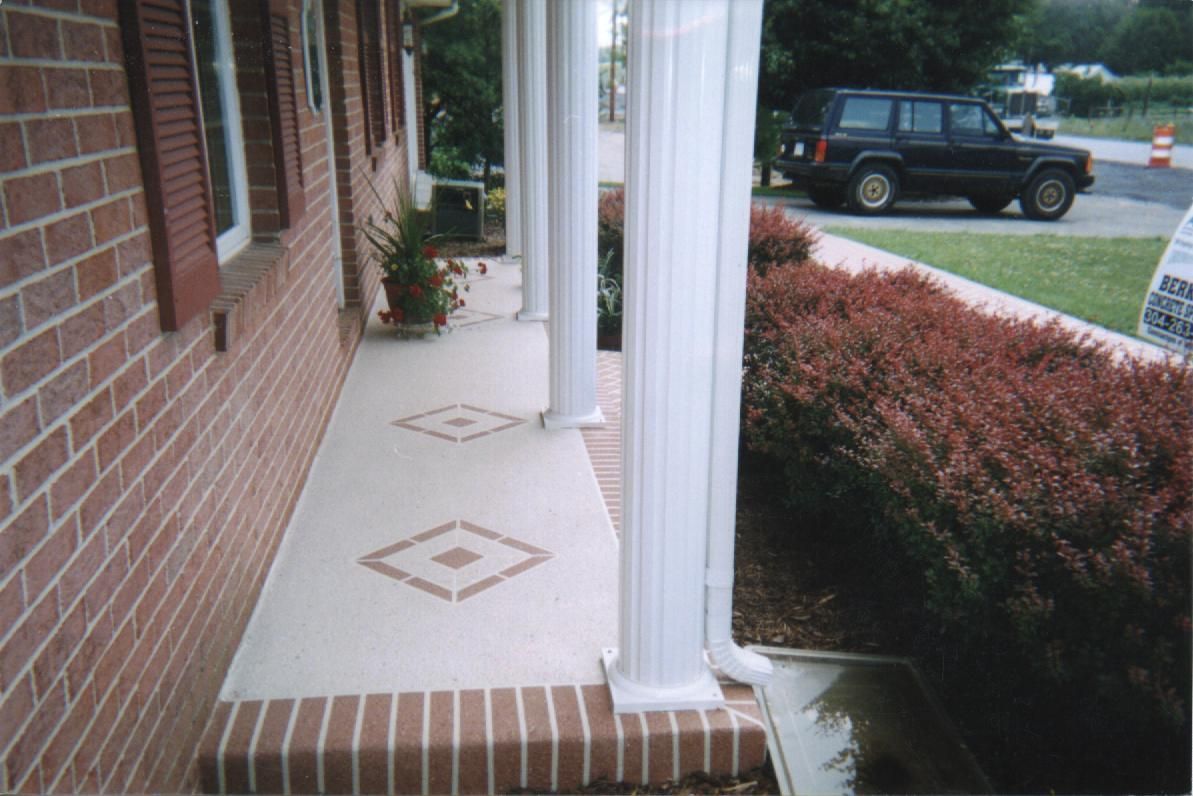 Brick porch walkway beside red shrubs and a parked SUV on a residential street.