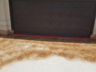 Dark brown garage door beside a snow-covered driveway with a red strip along the base