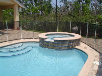 Backyard pool with a raised circular hot tub, curved steps, and a fenced patio area