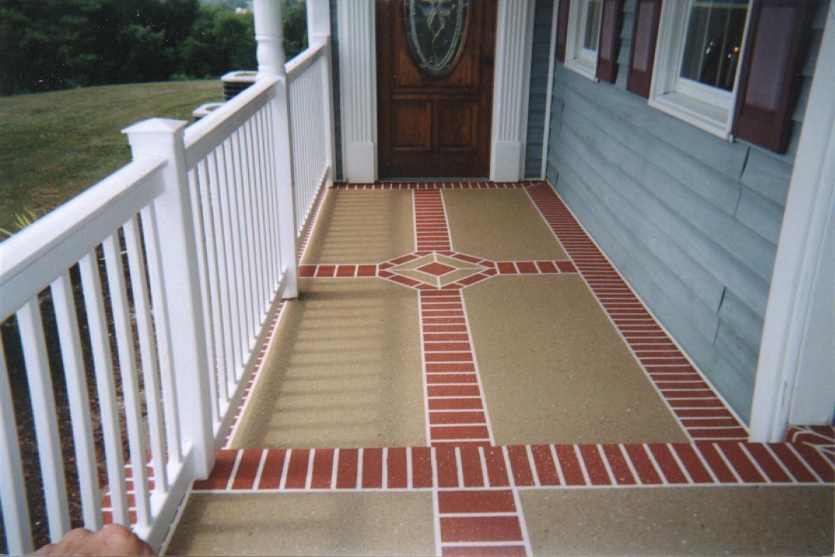 Brick-and-tan front porch with white railings leading to a wooden front door