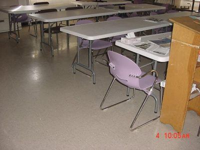 Empty cafeteria with tables and chairs, including a purple chair in the foreground.