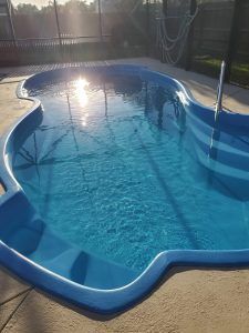 Backyard swimming pool with blue water and bright sunlight reflection