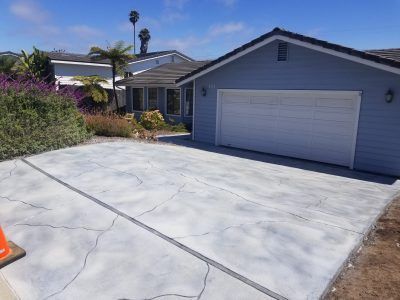 Driveway with a two-car garage and white gate, viewed from the street on a sunny day.