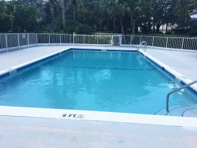 Outdoor swimming pool with blue water, white railings, and trees in the background
