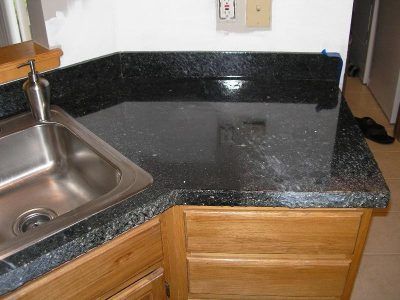 Black granite kitchen countertop with stainless steel sink and wooden cabinets