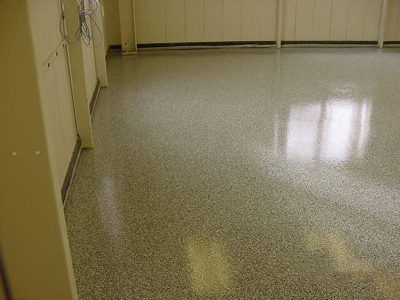 Empty hallway with beige walls and a glossy speckled floor reflecting window light