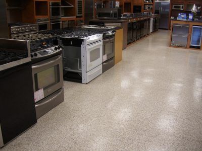 Appliance showroom with rows of stoves and ovens on a speckled floor