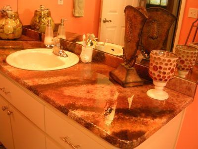 Bathroom vanity with sink, mirror, granite countertop, and decorative items in warm orange light