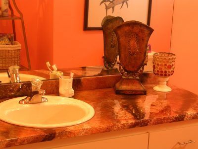 Orange-lit bathroom vanity with sink, mirror, and decorative candleholders on the countertop