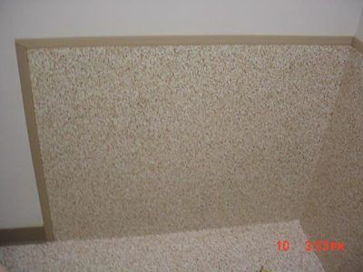 Speckled beige panel leaning against a wall on a carpeted floor.