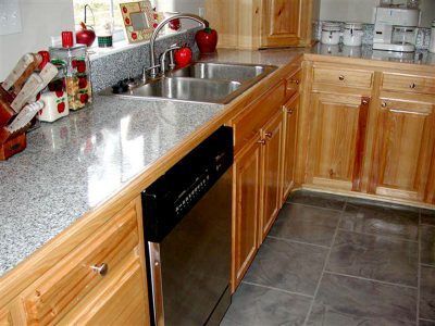 Modern kitchen with granite countertop, sink, wooden cabinets, black dishwasher, and red accents