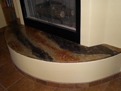 Curved stone hearth with brown and gray marbling in front of a fireplace