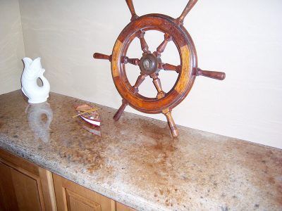 Wooden ship wheel and white ceramic pitcher on a speckled countertop