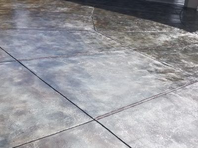 Wet concrete driveway with dark expansion joints and reflective patches