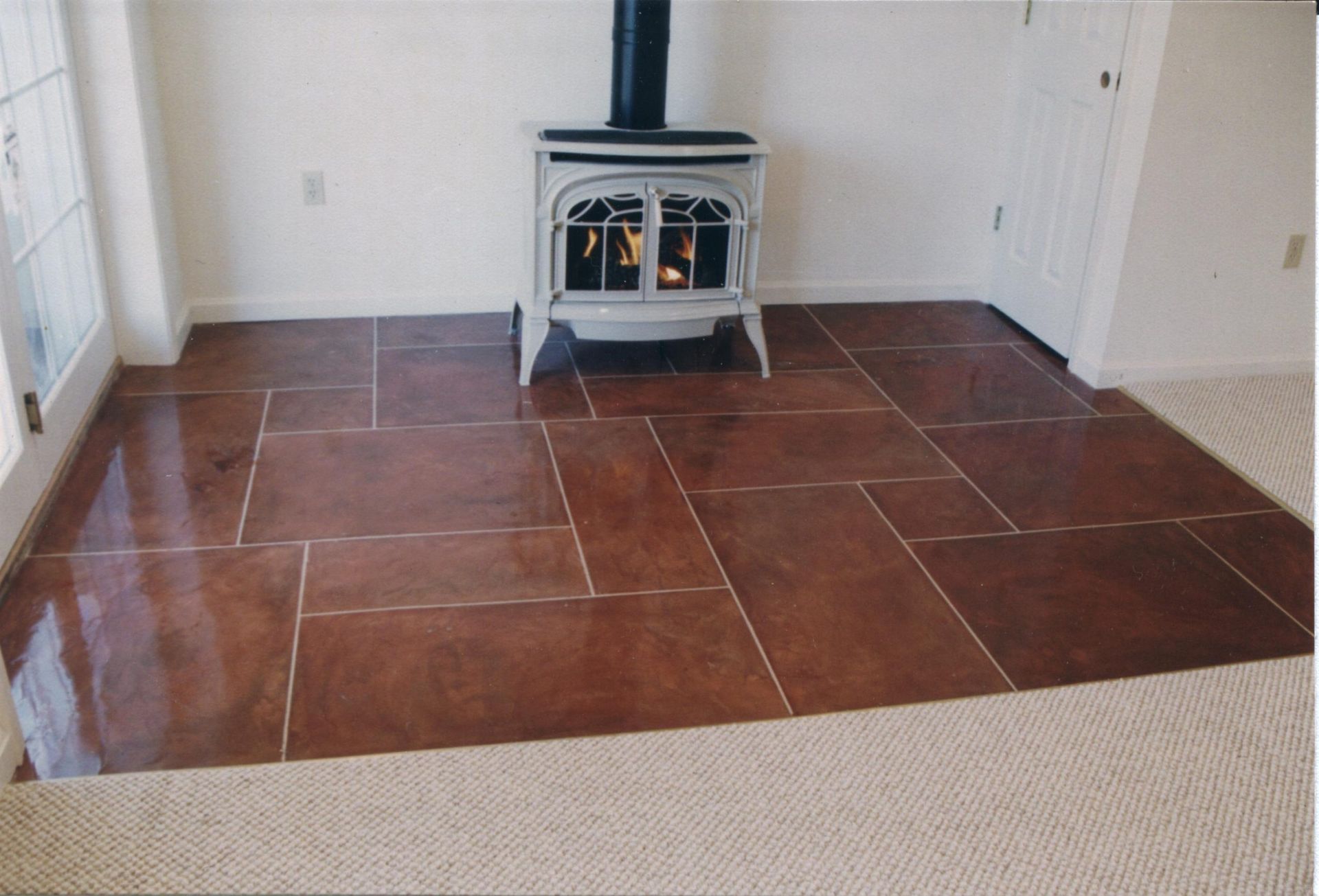 Living room with a wood stove on a reddish-brown tiled hearth and beige carpeted floor.