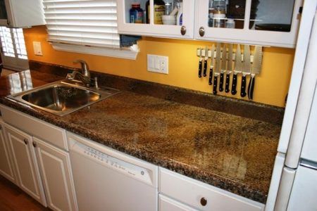 Kitchen counter with sink, speckled granite surface, yellow walls, and knife rack under a window